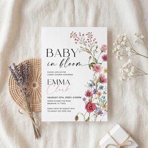 May include: Baby shower invitation with floral design. The invitation reads "Baby in Bloom" and includes details for Emma Clark's baby shower on August 12th, 2029. The invitation is decorated with pink, red, and purple flowers.