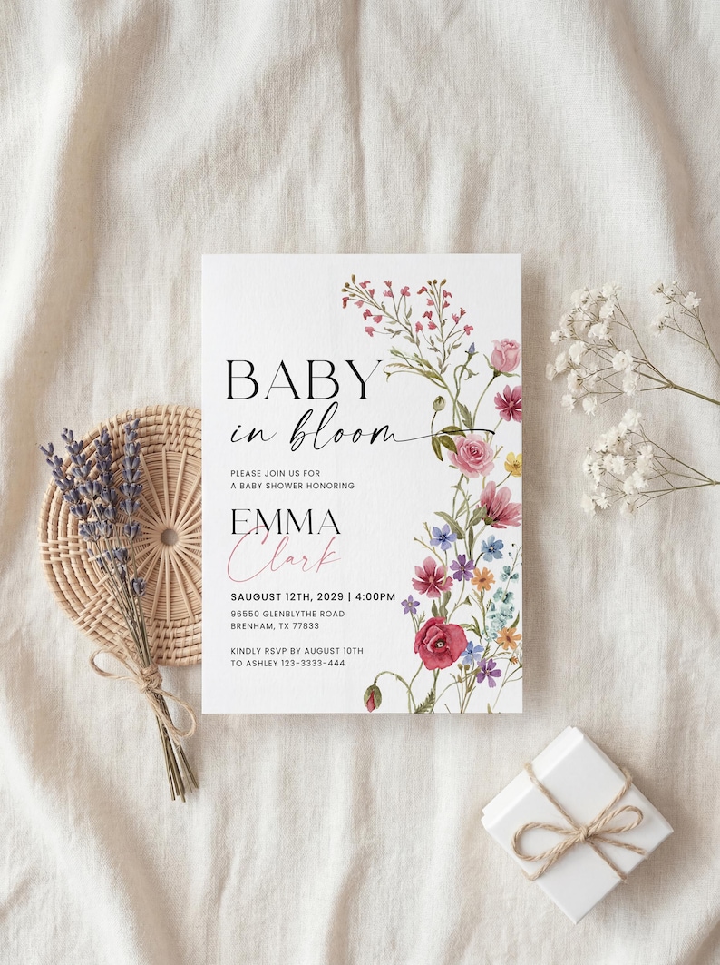 May include: Baby shower invitation with floral design. The invitation reads "Baby in Bloom" and includes details for Emma Clark's baby shower on August 12th, 2029. The invitation is decorated with pink, red, and purple flowers.