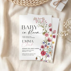 May include: Baby shower invitation with floral design. The invitation reads "Baby in Bloom" with the name "Emma Clark" and event details. The design features a watercolor floral border with pink, red, and purple flowers.