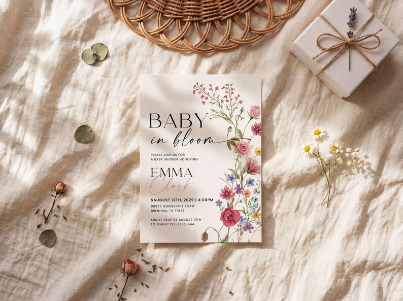 May include: A baby shower invitation with the text "BABY in bloom" and floral illustrations. The invitation includes the name "EMMA Clark" and event details. The invitation is on a cream-colored background with decorative elements.