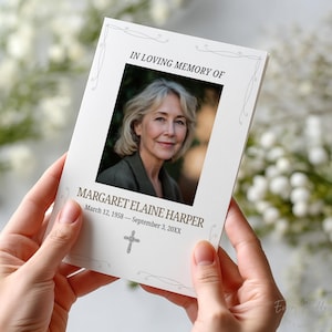 May include: A memorial card held by hands, featuring a photo of a woman with text that reads "IN LOVING MEMORY OF MARGARET ELAINE HARPER March 12, 1958 - September 3, 20XX" and a cross symbol. The card has decorative flourishes.