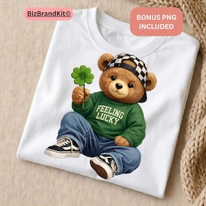 May include: White t-shirt featuring a cartoon teddy bear wearing a green sweater with "FEELING LUCKY" text, blue jeans, and a checkered hat. The bear holds a green four-leaf clover and wears black and white sneakers.