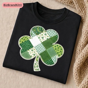 Puede incluir: Sudadera negra de cuello redondo con un gran diseño de trébol de retazos. El trébol está compuesto por varias telas verdes, incluyendo lunares, cuadros y estampados florales. El diseño está cosido con hilo blanco.