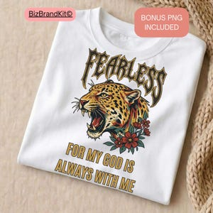 May include: White t-shirt featuring a detailed illustration of a roaring leopard with the word "FEARLESS" above it. Below the leopard is the text "FOR MY GOD IS ALWAYS WITH ME". The leopard has a brown and black spotted coat, with red flowers.