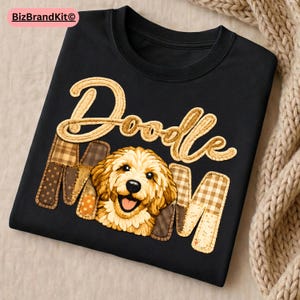 May include: Black t-shirt featuring the text "Doodle Mom" in a decorative font. The "MOM" letters are patchwork style, and the "O" in "Doodle" features a smiling golden doodle dog.