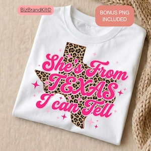 May include: White t-shirt featuring a pink and leopard print Texas graphic. The graphic includes the text "She's From Texas I Can Tell" in a pink, cursive font. Pink star accents surround the Texas graphic.