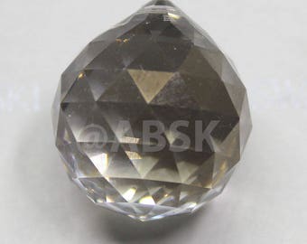 May include: A clear, faceted crystal ball with a teardrop shape. The ball is approximately 1 inch in diameter and has a smooth, polished surface.