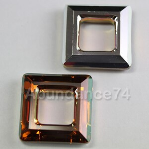 May include: Two square-shaped, iridescent crystal embellishments. One is a silver-tone metal frame with a clear centre. The other is a square crystal with a brown and green hue and a clear centre. The crystals are set against a white background.