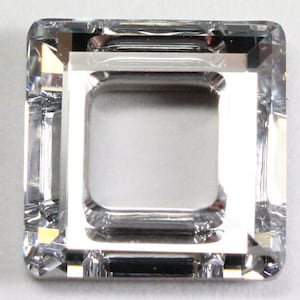 May include: A clear glass square bead with a square hole in the centre. The bead has a faceted design.