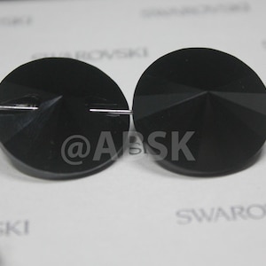 May include: Two black round crystal beads with a flat back and a pointed front. The beads are threaded on a silver wire.