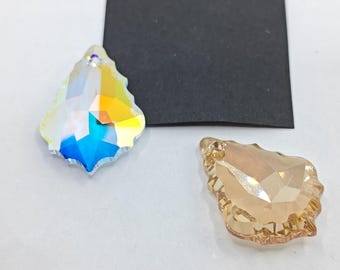 Op de afbeelding: Twee kristallen traanvormige hangers, één helder met regenboogkleuren en één amberkleurig.