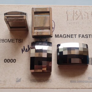 May include: Four silver-toned metal clasps with a geometric pattern. The clasps are rectangular and have a shiny finish. The text "MAGNET FAST" is visible on the card.