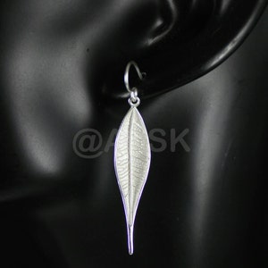 May include: Silver leaf dangle earrings. The earrings are shaped like a long, narrow leaf with a textured surface.