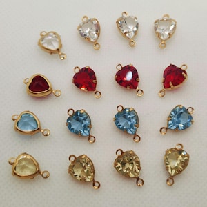 Puede incluir: Surtido de conectores de cristal en forma de corazón con engastes de tono dorado. Los conectores están disponibles en transparente, azul claro, amarillo y rojo.