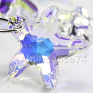 May include: A clear iridescent crystal starfish charm with a blue center. The charm has a hole at the top for attaching to a necklace or bracelet.