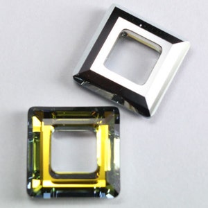 May include: Two square-shaped crystal beads with a hole in the center. One bead is clear with a silver-colored frame, and the other bead is a dark green color with a gold-colored frame.