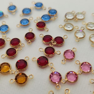 May include: Assortment of colorful glass beads with gold metal connectors. The beads are in shades of red, blue, pink, and clear. The connectors have two loops for attaching to jewelry or other crafts.
