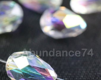 Op de afbeelding: Een groep van iriserende, heldere glazen traanvormige kralen. De kralen zijn gefacetteerd en hebben een regenboogkleurige glans.
