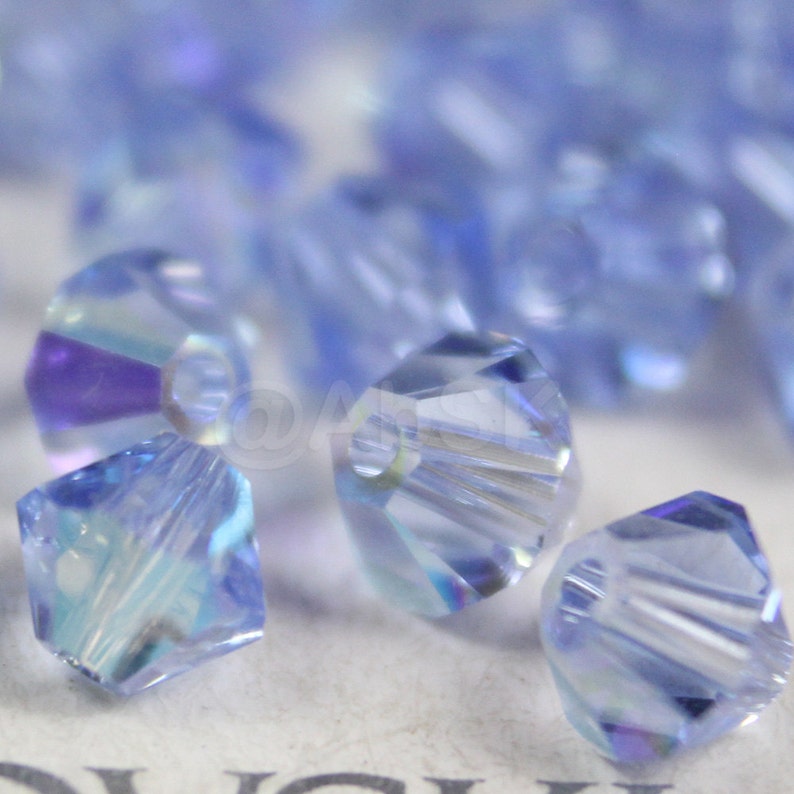 Peut inclure: Gros plan sur un groupe de perles en cristal bleu clair. Les perles sont facett&eacute;es et ont une finition claire et iris&eacute;e.