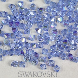 Peut inclure: Gros plan sur un tas de perles en cristal bleu clair. Les perles sont facett&eacute;es et ont une finition chatoyante. Les perles sont &eacute;tiquet&eacute;es "SWAROVSKI".