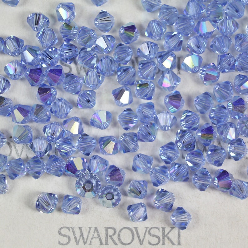 Peut inclure: Gros plan sur un tas de perles en cristal bleu clair. Les perles sont facett&eacute;es et ont une finition chatoyante. Les perles sont &eacute;tiquet&eacute;es "SWAROVSKI".