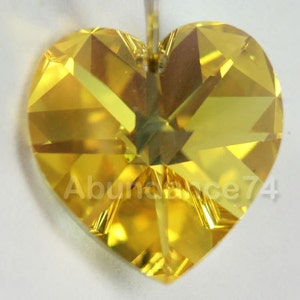 May include: A yellow heart-shaped crystal with a faceted design. The crystal has a hole at the top for hanging.