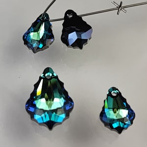 May include: Four teardrop-shaped crystal pendants in shades of blue and green. The pendants have a faceted design and a hole at the top for hanging.
