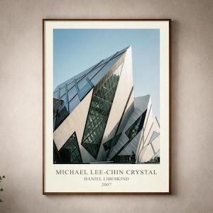 May include: A framed architectural print featuring the Michael Lee-Chin Crystal building designed by Daniel Libeskind in 2007. The image displays sharp, angular metallic panels and large glass windows against a clear blue sky, with text below.