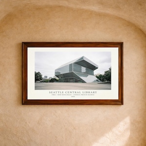 May include: A framed architectural print of the Seattle Central Library featuring a geometric glass and steel structure. The text below reads SEATTLE CENTRAL LIBRARY, OMA / REM KOOLHAAS - JOSHUA PRINCE-RAMUS, 2004. The frame is dark brown wood.