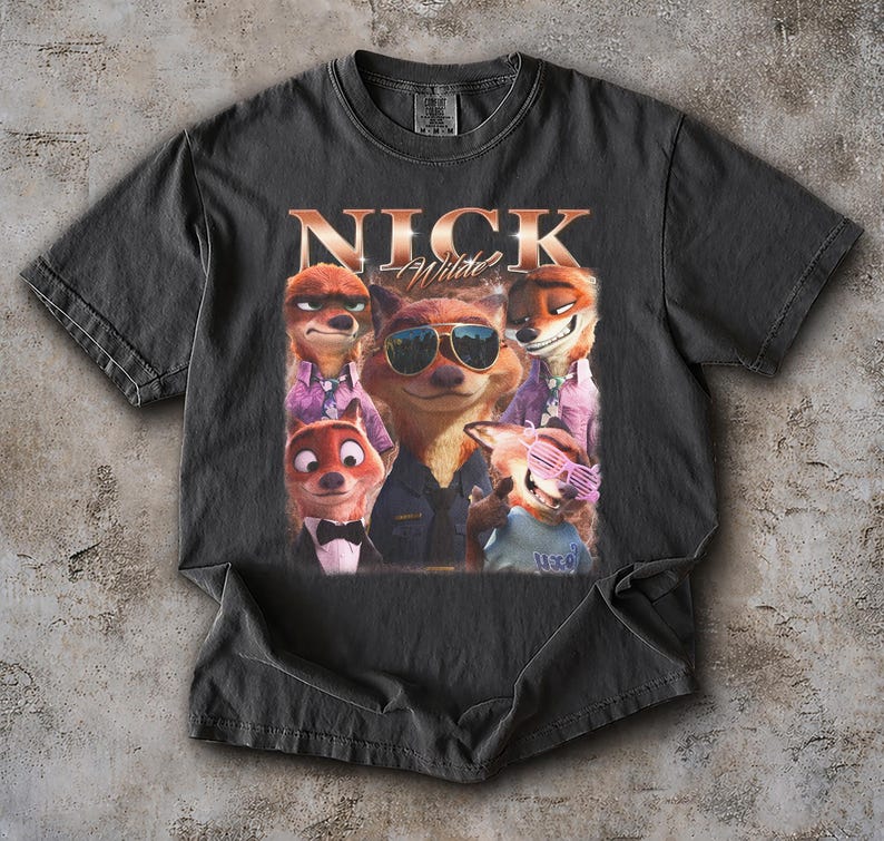 May include: Dark gray t-shirt featuring a graphic of several cartoon foxes, with the text "NICK Wilde" in a gold font. The foxes are wearing sunglasses and formal attire. The shirt is made of a soft material.