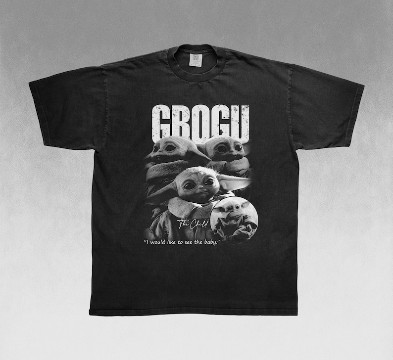 May include: Black t-shirt featuring a graphic of Grogu, also known as The Child, from The Mandalorian. The design includes the word "GROGU" in large white letters and a portrait of Grogu. The text "I would like to see the baby" is also included.
