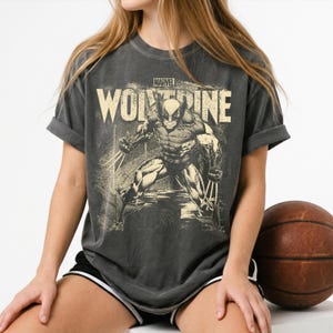 Peut inclure: Un t-shirt gris anthracite à manches courtes avec une impression graphique du personnage Marvel Wolverine dans une position accroupie avec des griffes étendues. Le texte MARVEL WOLVERINE est imprimé en police crème vieillie.
