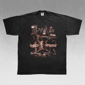 Puede incluir: Camiseta negra con un diseño gráfico de la película Piratas del Caribe. El diseño incluye una calavera, espadas cruzadas y un barco con piratas. La camiseta es de cuello redondo y tiene mangas cortas.