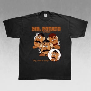 May include: Black t-shirt featuring a graphic of Mr. Potato Head with the text "MR. POTATO HEAD" in brown. The design includes multiple Mr. Potato Head characters and the phrase "Hey, watch it, buddy!"