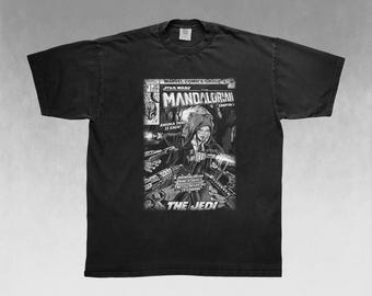 Op de afbeelding: Zwart T-shirt met een stripboekachtige afbeelding. De afbeelding bevat de tekst "MARVEL COMICS GROUP STAR WARS THE MANDALORIAN" en een illustratie van een personage met de tekst "ANSOKA TANO IS BACK" en "THE JEDI".