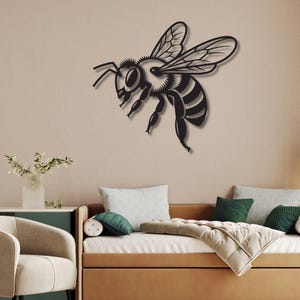 May include: A black metal bee wall art piece. The bee is depicted in flight, with detailed wings and body segments. The artwork is mounted on a neutral-colored wall, creating a striking contrast. This decorative piece adds a touch of nature-inspired decor.