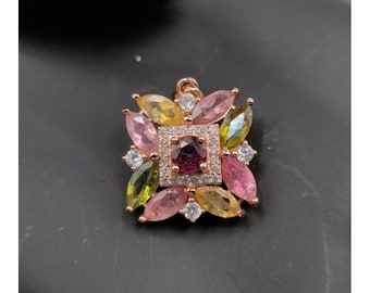 May include: A rose gold pendant with a square, multi-colored gemstone design. The center features a dark red square stone surrounded by smaller clear stones. The outer design includes pink, yellow, and green petal-shaped stones.