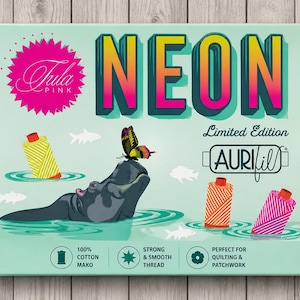 May include: A teal box with the word "NEON" in a gradient design, and "Tula Pink" branding. The image shows a hippo, a butterfly, and thread spools. Text includes "Limited Edition" and "AURIfil".