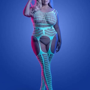 Könnte beinhalten: Ein hellblauer Netz-Body mit passenden Oberschenkelstrümpfen. Das einteilige Kleidungsstück hat ein großes offenes Webmuster. Das Model steht vor einem blauen Hintergrund mit rosa und lila Beleuchtung.