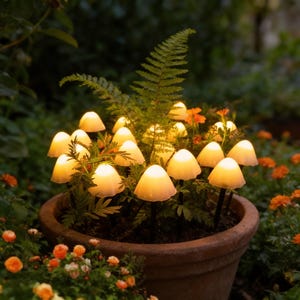 May include: A terracotta pot filled with greenery and illuminated mushroom-shaped lights. The lights have a soft, warm glow, creating a whimsical garden scene. Orange flowers and ferns surround the pot, adding color and texture.