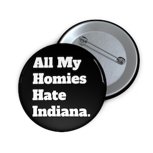 May include: A black button with the text "All My Homies Hate Indiana" in white. The button is round and has a metal pin back. Another button is partially visible in the background.