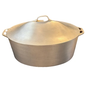 Puede incluir: Una olla grande de cocina de color plateado con tapa a juego. La olla tiene un cuerpo redondeado y una tapa con asa. La olla tiene dos asas a cada lado. La olla es de metal.