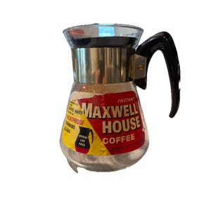 May include: Vintage Maxwell House Coffee pot with a black handle and gold-colored metal accents. The glass carafe features a red, yellow, and white label with the Maxwell House Coffee logo and text. The carafe is heatproof.