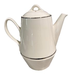 May include: Cream-colored ceramic teapot with a silver trim around the lid and base. The teapot has a curved handle and a spout for pouring. The lid has a small loop handle. A classic design for serving tea.