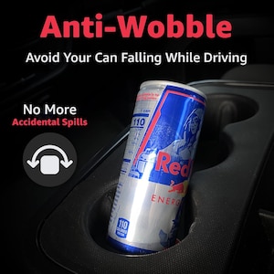 May include: A black car cup holder with a silver and blue Red Bull energy drink can. The image includes the text "Anti-Wobble" and "Avoid Your Can Falling While Driving". The can has 110 calories.