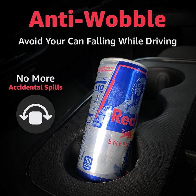 May include: A black car cup holder with a silver and blue Red Bull energy drink can. The image includes the text "Anti-Wobble" and "Avoid Your Can Falling While Driving". The can has 110 calories.