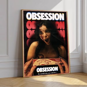 Puede incluir: Un póster enmarcado que muestra una escena cinematográfica oscura de una persona con sangre en la cara, sosteniendo una pequeña caja con la etiqueta One Wish Willow. La palabra OBSESSION aparece en letras blancas grandes arriba y abajo, con el texto Be careful who you wish for.