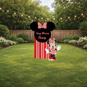 May include: A Minnie Mouse-themed birthday yard decoration. The decoration features a black Minnie Mouse head with a red bow, a red and white striped base, and a Minnie Mouse cutout. The words "Happy Birthday Avery" are on the decoration.