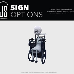 May include: A cutout sign featuring a stylized, bald, grey-skinned character with glasses sitting in a black wheelchair. The top header displays the text JS DISPLAYS SIGN OPTIONS, Metal Stakes > Outdoor Use, Easelback > Indoor Use (Sold Seperately).