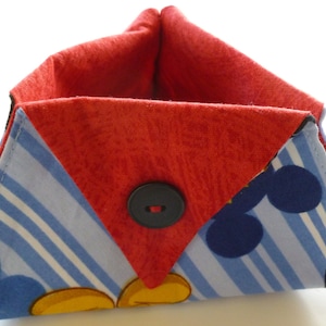 May include: A red and blue fabric storage basket with a Mickey Mouse design. The basket has a single black button on the front.